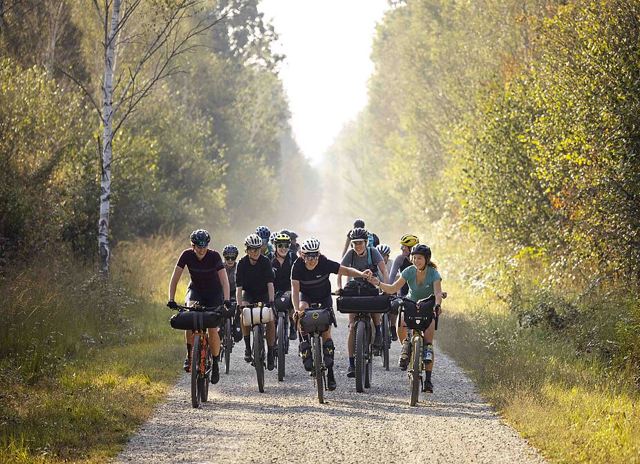 Radfahrende mit komoot Radfahrende im Wald auf breitem Weg