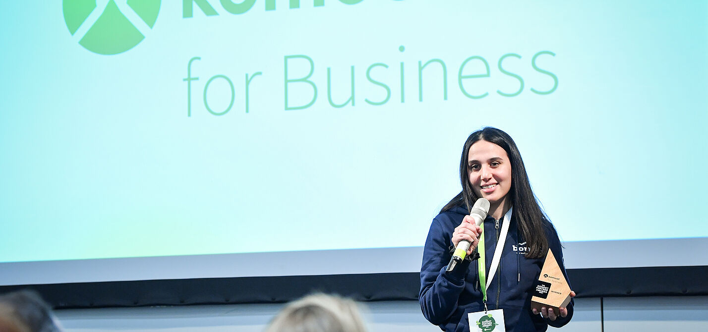 Frau redet in Mikrofon mit komoot Partner Award 2024 in der Hand