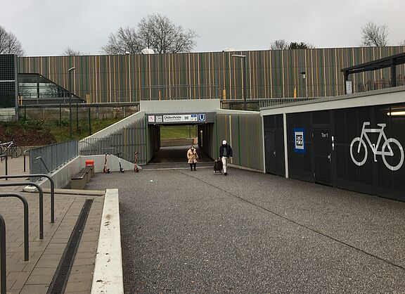 Unterführung am U-Bahnhof Oldenfelde, links Fahrradbügel, rechts Fahrradboxen, mittig eine breite Rampe mit zwei Personen zu Fuß.