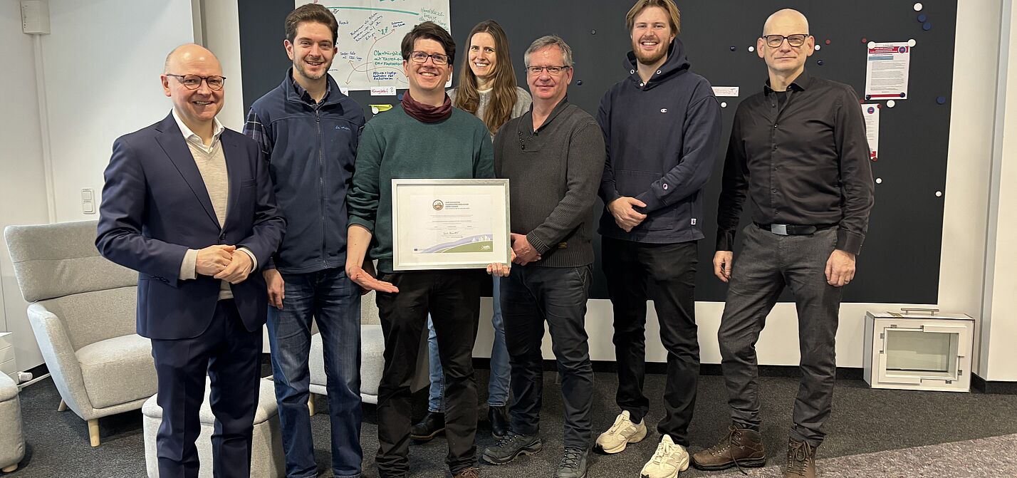 Eine Gruppe von Menschen mit einem gerahmten Zertifikat