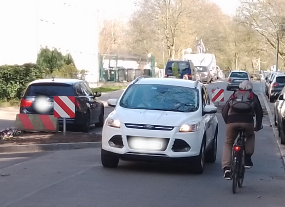 Ein Radfahrer wird von einem Autofahrenden bedrängt.