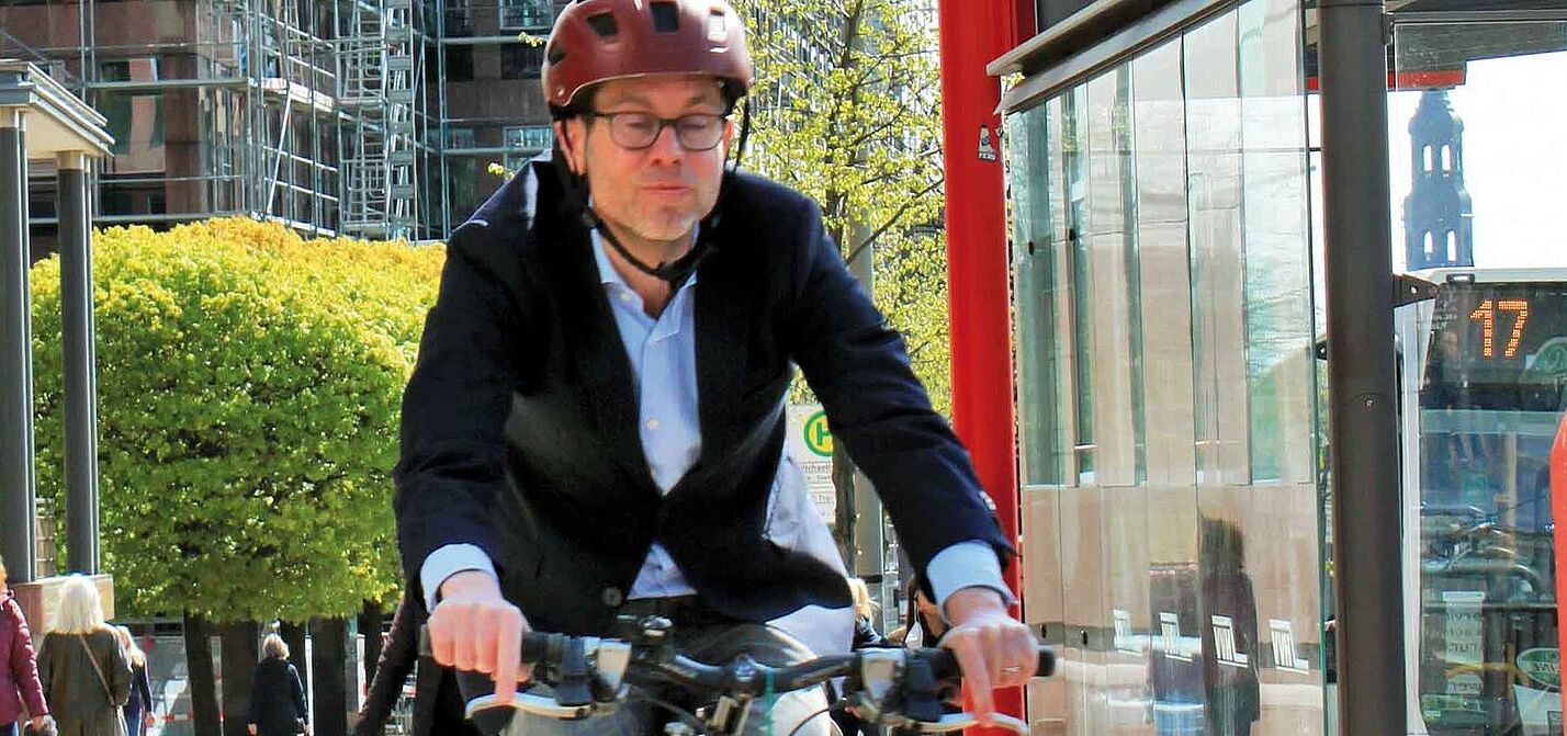 Oberstaatsanwalt Björn Ziera, auf seinem Fahrrad mit Fahrradhelm, Jeans und Sakko bekleidet.