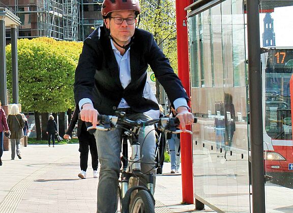 Oberstaatsanwalt Björn Ziera, auf seinem Fahrrad mit Fahrradhelm, Jeans und Sakko bekleidet.