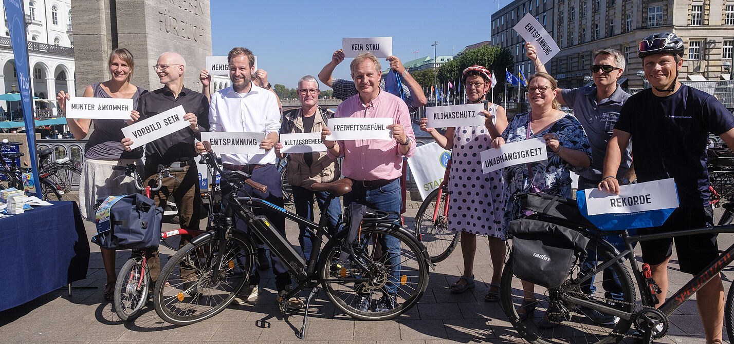SR_2023_Auftakt Eine Gruppe Menschen zur Eröffnung des STADTRADELN. Sie halten Schilder ins Bild mit Gründen warum sie beim STADTRADELN dabei sind.