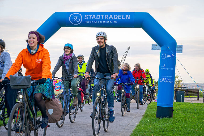 2024-09-30_Abradeln_fuers_Stadtradeln Gruppe Radfahrender fährt durch einen Torbogen