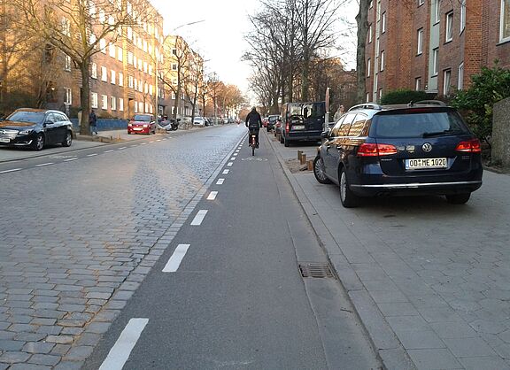 nach dem Umbau: Radfahrer*innen fahren im Sichtfeld der Autofahrer*innen auf den Schutzstreifen aus Asphalt.