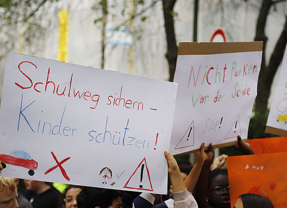 Kinder halten bei deiner Demo Schilder hoch und fordern sichere Schulwege