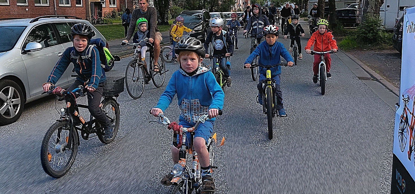 20230924_Kidical_Mass Eine gruppe Kinder fährt mit dem Fahrrad auf der Fahrbahn, im Hintergrund sind erwachsene Begleitpersonen zu sehen