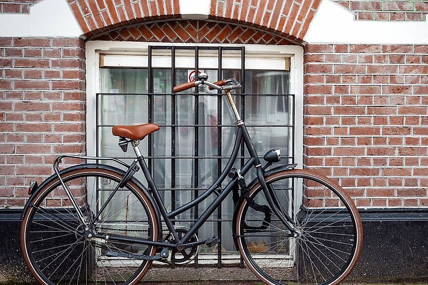 Fahrradabstellanlagen Ein Fahrrad vor einem vergitterten Fenster angeschlossen