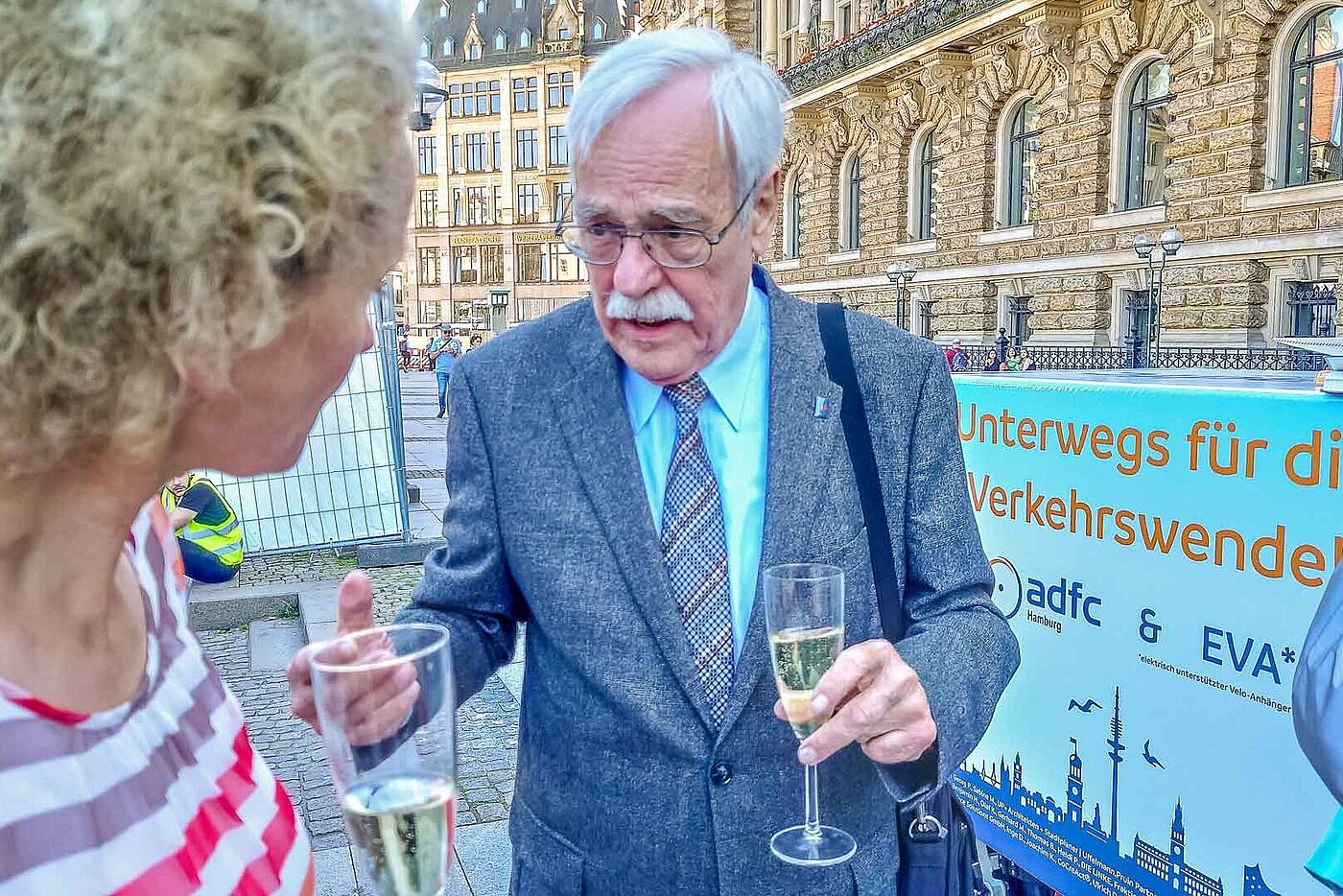 Uwe Jancke mit einem Sektglas in der Hand, im Gespräch mit einer blonden Frau