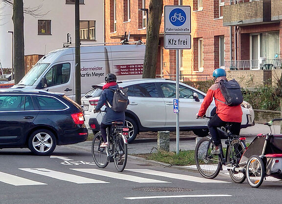 Ein Auto versperrt Radfahrenden den Weg in einer Fahrradstraße direkt hinter dem Verkehrszeichen "Fahrradstraße, Autos frei"