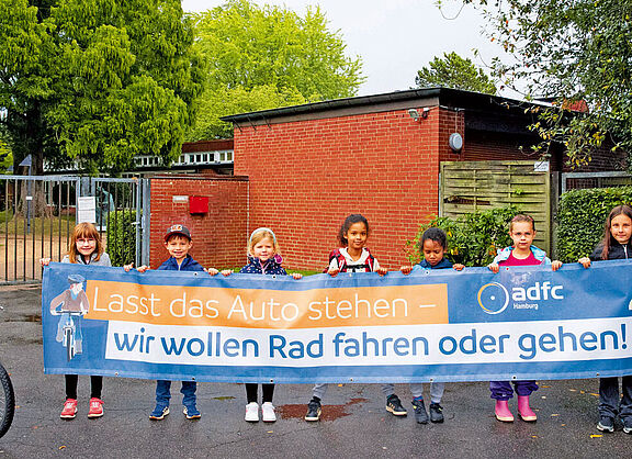 Demo Kinder demonstrieren vor ihrer Schule für weniger Autoverkehr