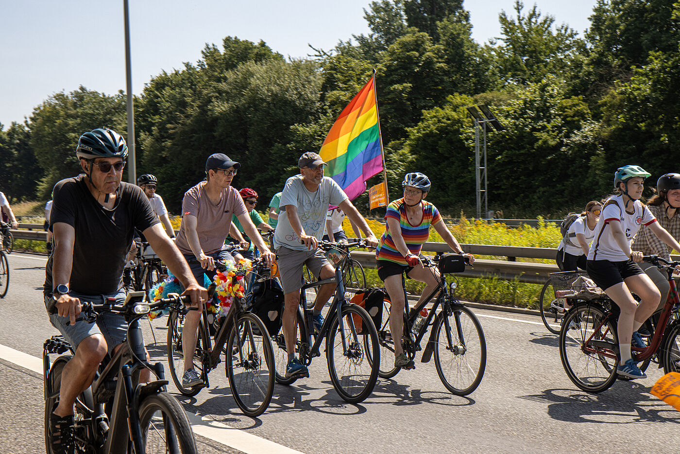 Radfahrende bei der Sternfahrt mit Regenbogenflagge