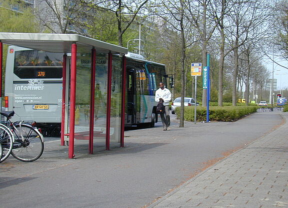 Ein breiter Radweg führt hinter dem Warteplatz für Fahrgäste entlang. Daneben verläuft der breite Gehweg.