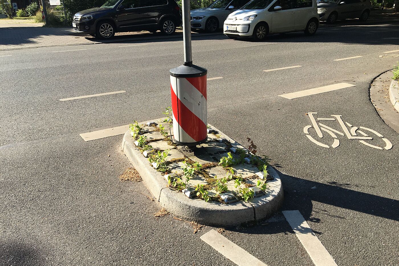 Nahaufnahme: Kleine Verkehrsinsel mit einem Rundpoller großen Durchmessers