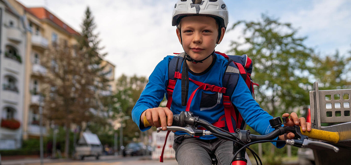 Schulweg per Fahrrad Junge mit Schulranzen auf dem Fahrrad