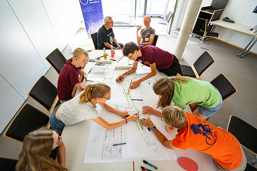 Aktivenmanagement mehrere Personen sind über einem Arbeitstisch gebeugt und bearbeiten gemeinsam Dokumente