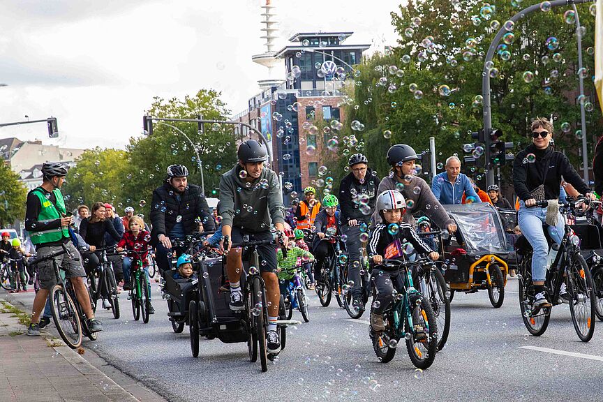 Kidcial Mass im Bubbleregen Teilnehmende der Familien-Fahrraddemo Kidical Mass fahren durch einen Seifenblasen-Regen