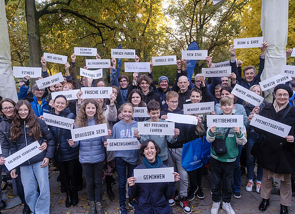 Die Gäste der Abschlussveranstaltung halten Schilder mit ihrem eigenen Grund für die Teilnahme am STADTRADELN 2023