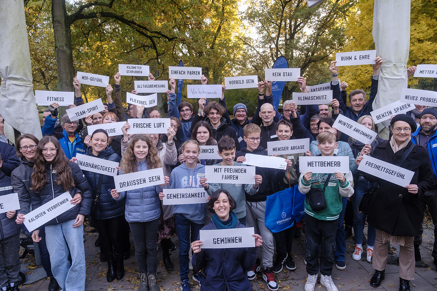 Die Gäste der Abschlussveranstaltung halten Schilder mit ihrem eigenen Grund für die Teilnahme am STADTRADELN 2023
