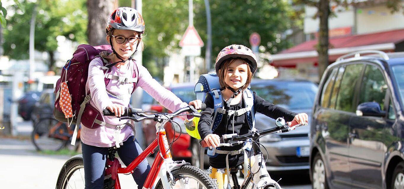 ADFC__c__April_Agentur_Schulstart 2 Kinder mit Fahrrädern und Schulranzen