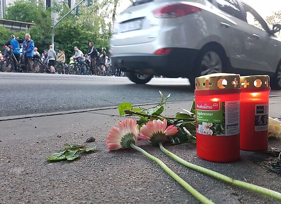Blumen und Kerzen auf einer Fahrbahn in Gedenken an einen getöteten Radfahrenden