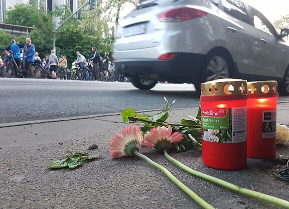 Blumen und Kerzen auf einer Fahrbahn in Gedenken an einen getöteten Radfahrenden