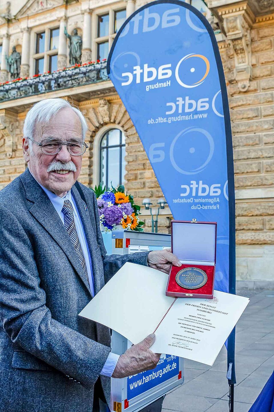 Medaille Uwe Jancke präsentiert die Medaille mit Urkunde vor dem Hamburger Rathaus