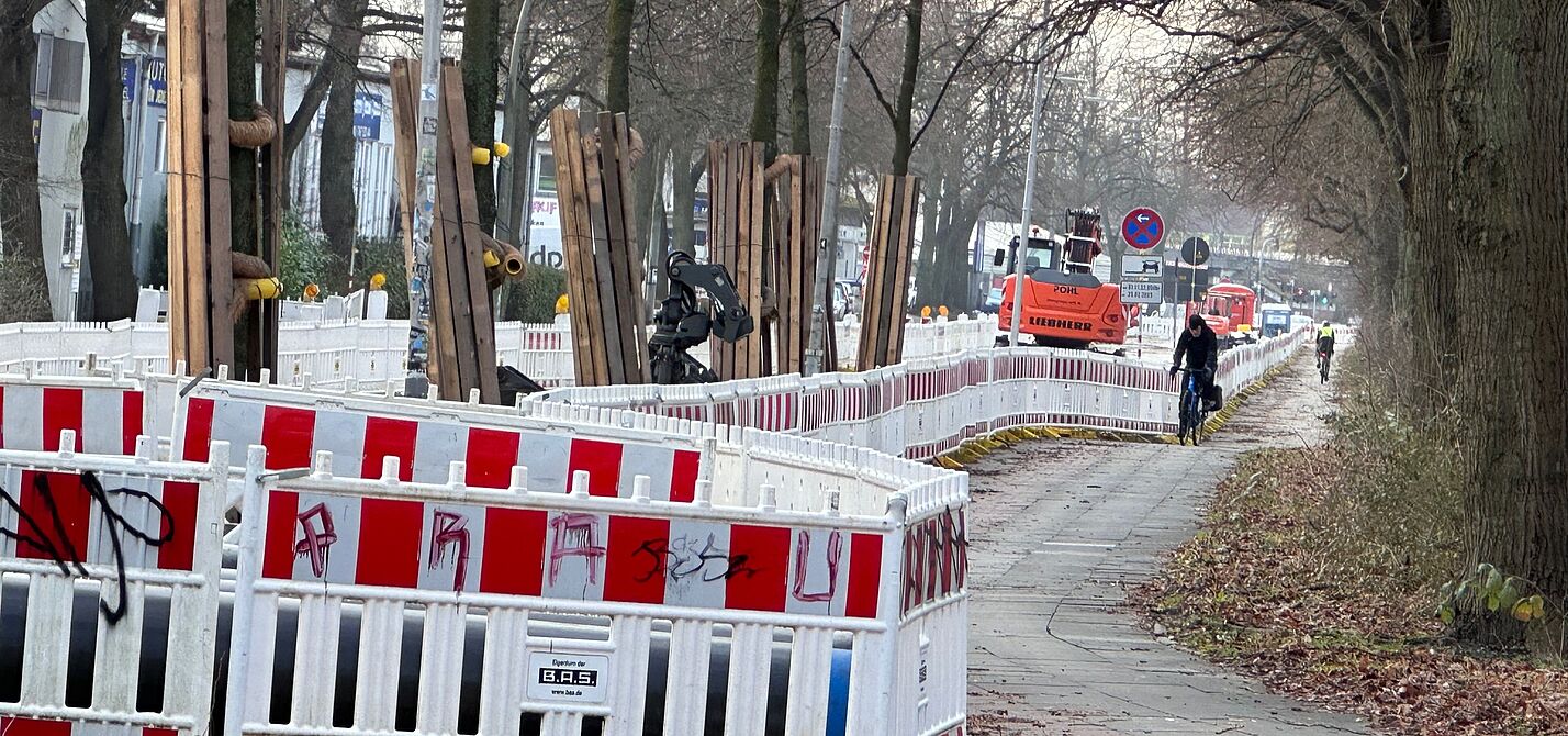 Radfahrende auf Gehweg neben einer Baustelle
