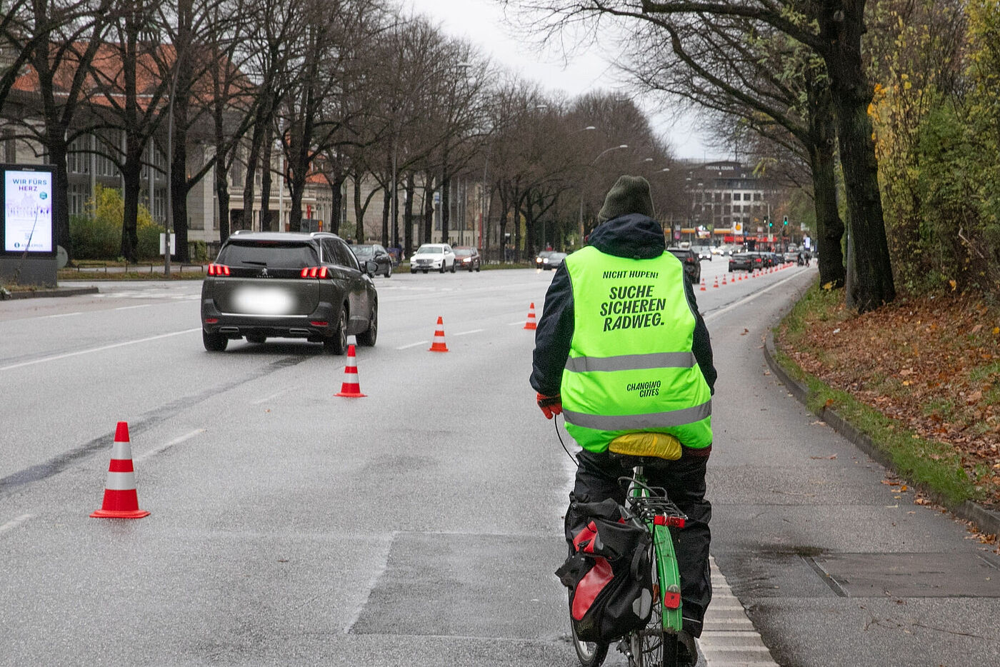 Radfahrende Person mit "Suche sicheren Radweg" auf der Warnweste