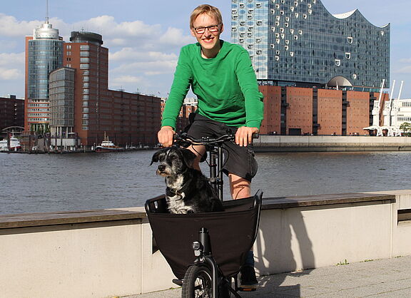 Junger Mann mit Hund im Lastenrad