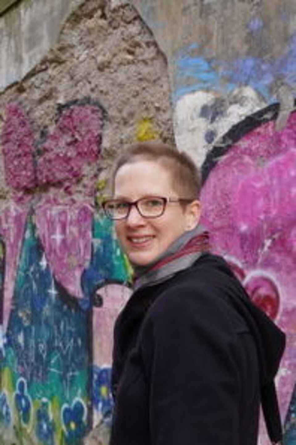 Kathrin Bild von Kathrin vor einer mit Graffiti verzierten Mauer