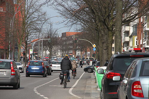 Ein PKW fährt neben einem Fahrrad-Schutzstreifen in Hamburg –   - Mobilität in Szene gesetzt