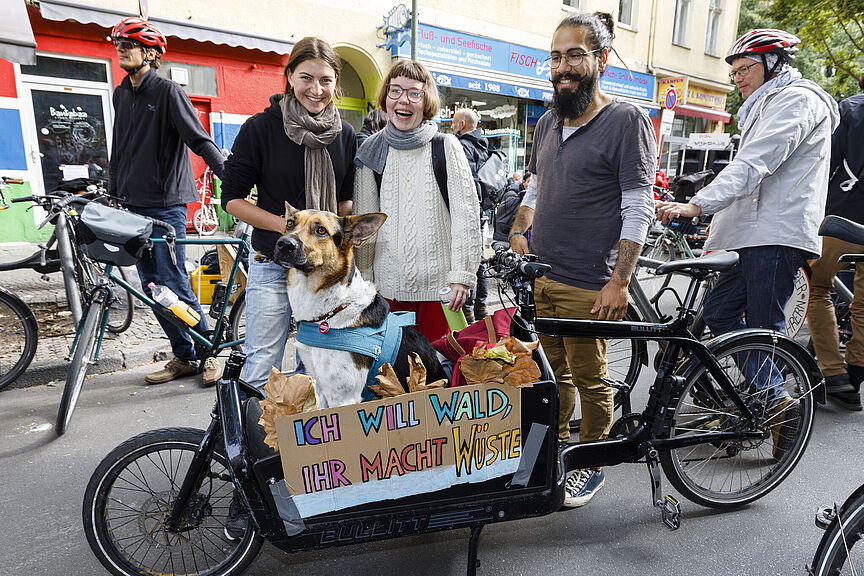 Lastenrad_Pepole Einige junge Menschen stehenum ein Lstenrad herum. Ein Schild mit der Aufschrifft: Ich will Wald - Ihr macht Wüste