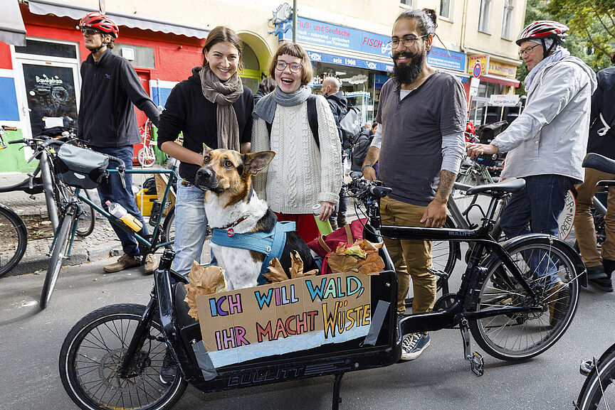 Lastenrad_Pepole Einige junge Menschen stehenum ein Lstenrad herum. Ein Schild mit der Aufschrifft: Ich will Wald - Ihr macht Wüste