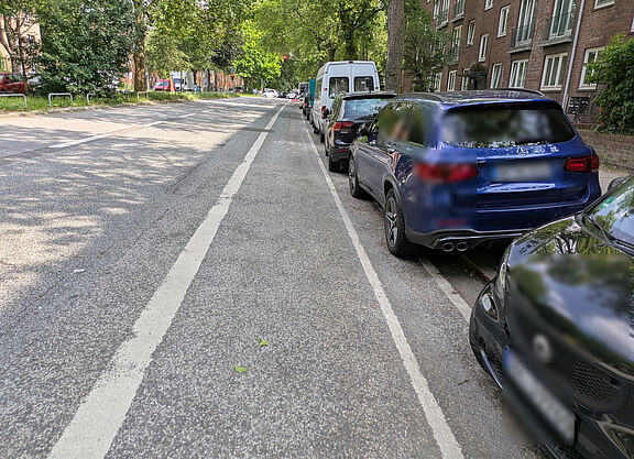 Washingtonallee_18.06.2025 Fahrzeuge parken auf dem Sicherheitstrennstreifen, dadurch ist der Radfahrstreifen direkt in der "Dooring"-Zone.