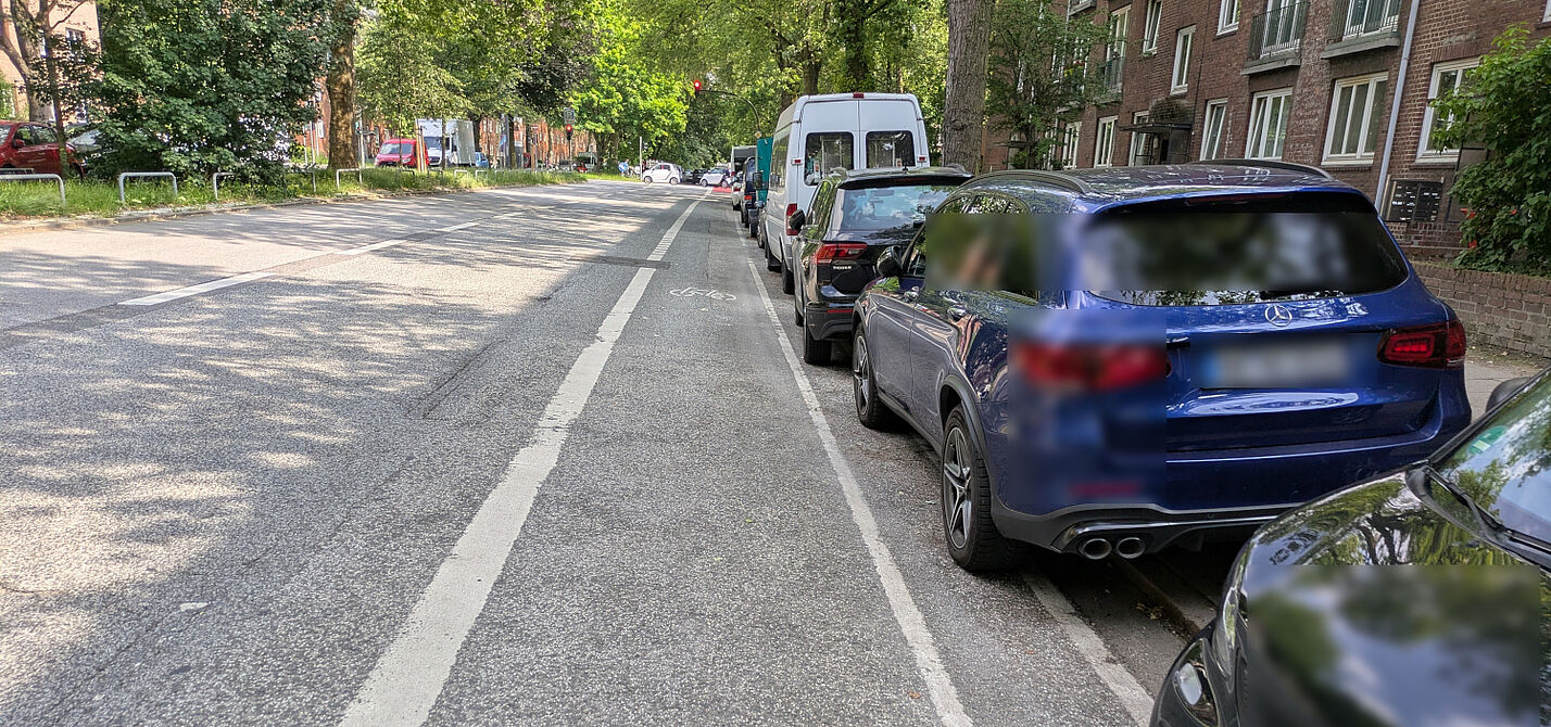 Washingtonallee_18.06.2025 Fahrzeuge parken auf dem Sicherheitstrennstreifen, dadurch ist der Radfahrstreifen direkt in der "Dooring"-Zone.