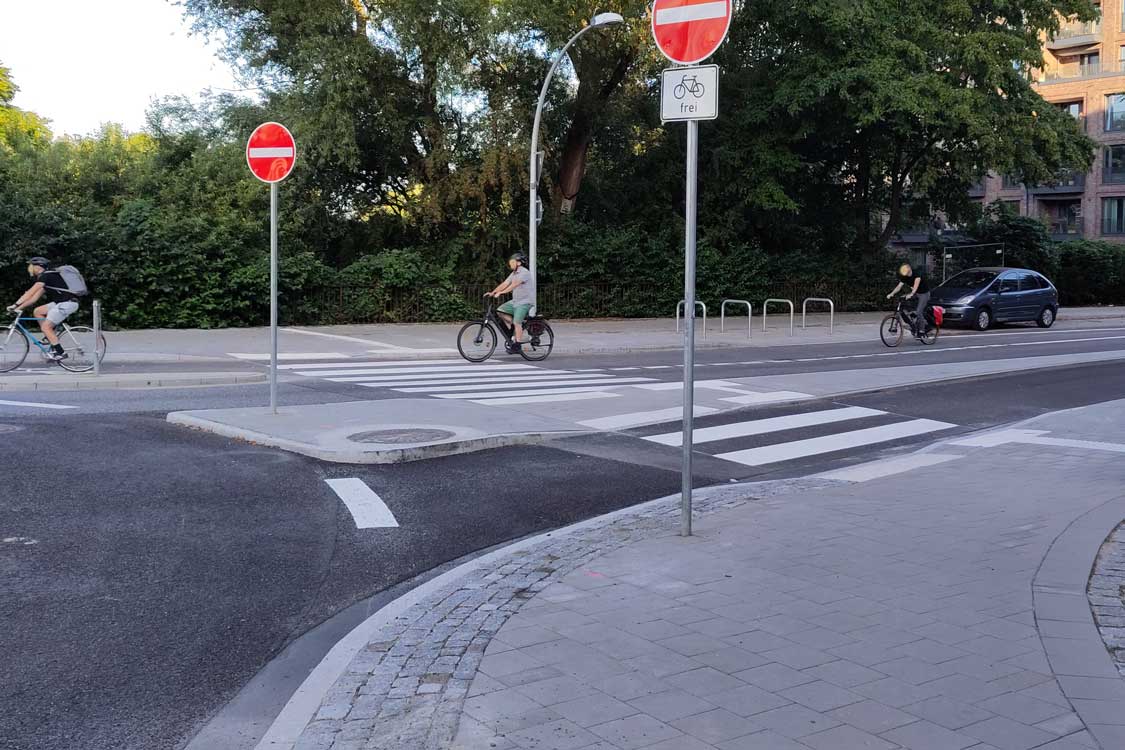 Die Einmündung Poppenhusenstraße - Hufnerstraße ist durch einen Mini-Kreisverkehr gelöst. Die Ampeln sind abgebaut, rundherum gibt es Fußgängerüberwege über die Fahrbahnen und die Radfahrstreifen, die Zufußgehende bequem und nun ohne Wartezeiten queren lassen.