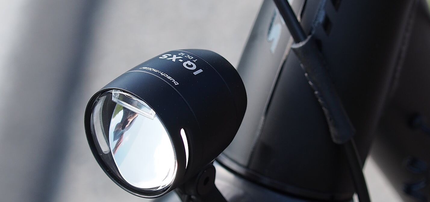 Schwarzer LED-Fahrradscheinwerfer am silbernen Fahrradlenker montiert.