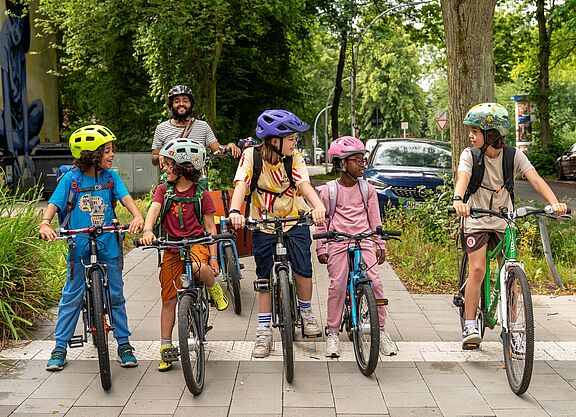 eine Kindergruppe auf Rädern steht auf dem Weg, alle schauen sich an.